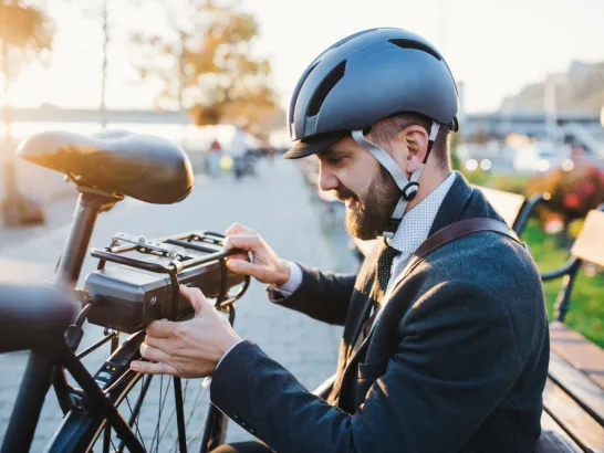 Ein Radfahrer bringt ein Akku an seinem E-Bike an.