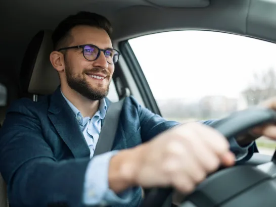 Ein Mann fährt fröhlich sein Auto.