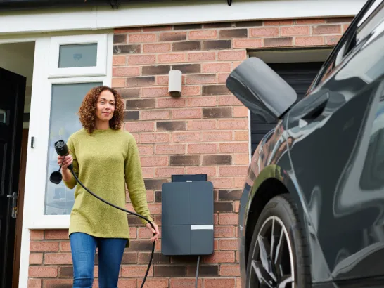 Frau schließt ihr Elektroauto an die Wallbox an.