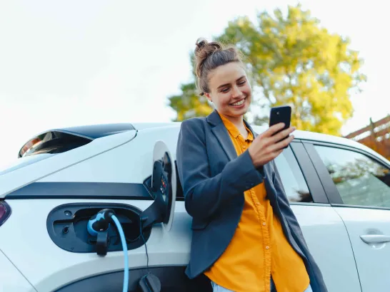 Frau lädt Elektroauto.