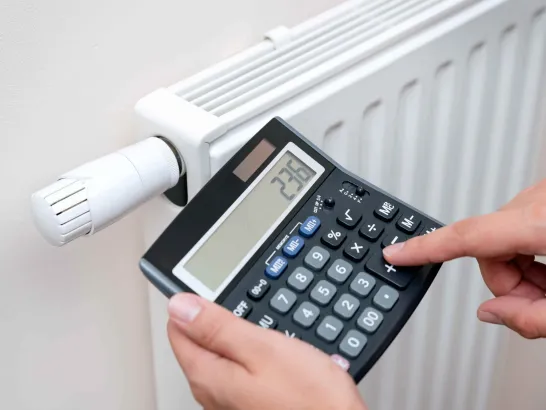 Ein Mensch rechnet mit einem Taschenrechner seine Heizkosten aus.