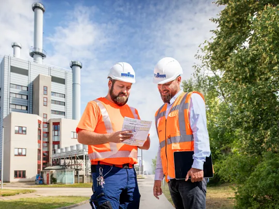 Zwei Stadtwerke-Mitarbeiter stehen vor dem Heizkraftwerk Schwerin Süd