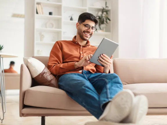 Mann sitzt mit seinem Tablet auf dem Sofa