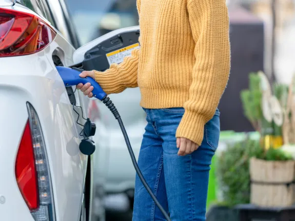 Eine Frau schließt ihr Elektroauto an eine Ladestation an.