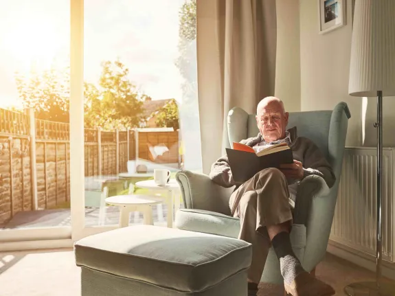 Mann liest ein Buch und hat es gemütlich warm Zuhause.