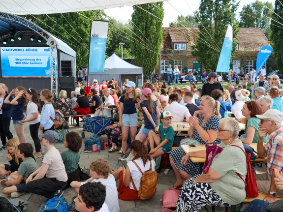 Eine Menschenmenge sitzt auf Bänken um die Stadtwerke-Bühne auf dem Insel- und Strandfest.