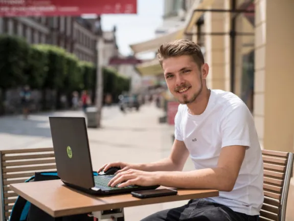 Mann sitzt vor seinem Laptop im Café
