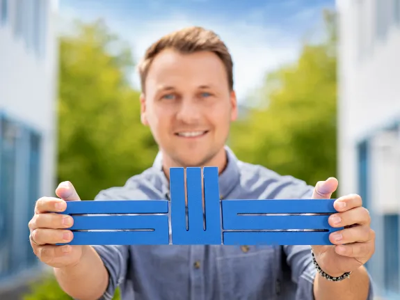Ein junger Mann hält das Logo der Stadtwerke Schwerin mit beiden Händen in die Kamera.