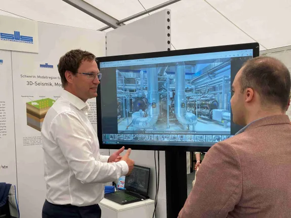 Zwei Männer stehen vor einem großen Monitor