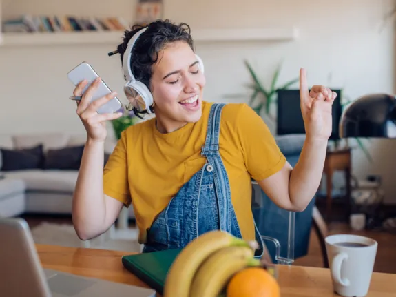 Junge Frau mit Kopfhörern hört Musik von ihrem Handy