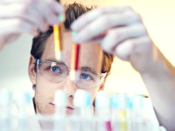 Ein Chemielaborant schaut sich Reagenzgläser an.