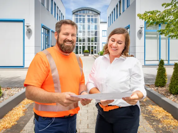 Zwei Mitarbeitende der Stadtwerke stehen vor dem Hauptgebäude.
