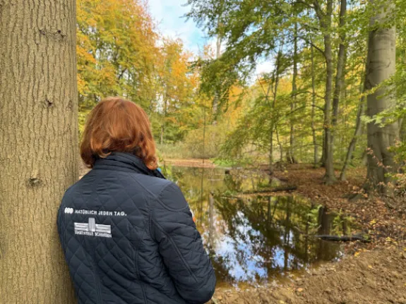 Eine Stadtwerkemitarbeiterin lehnt sich an einen Baum.