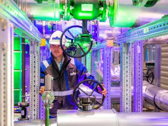 Stadtwerkemitarbeiter im Wärmepumpenraum einer Geothermie-Anlage.