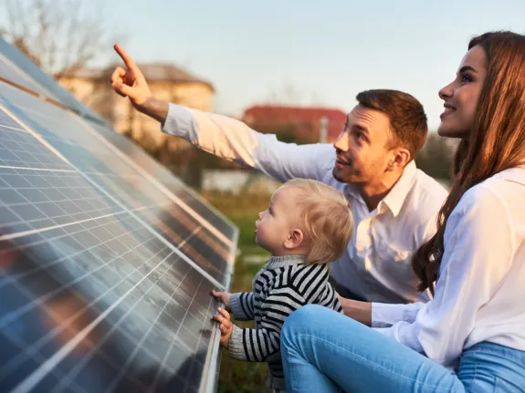 Ein Mann zeigt seiner Familie die Sonnenkollektoren einer Solaranlage.