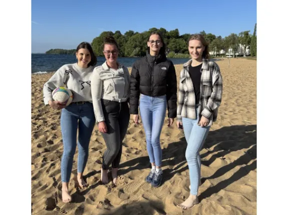 Vier junge Frauen am Strand mit einem Beachvolleyball