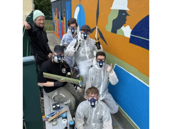 Junge Leute in Schutzkleidung beim Arbeiten mit Graffiti