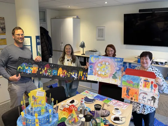 Ein Mann und drei Frauen präsentieren die Werke einer Malaktion für Kinder