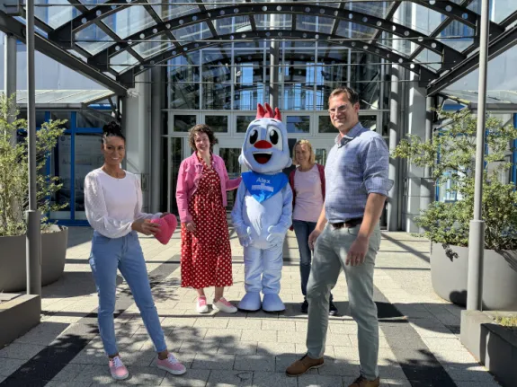 Eine junge Frau übergibt ein rosa Plüschherz an einen Mann