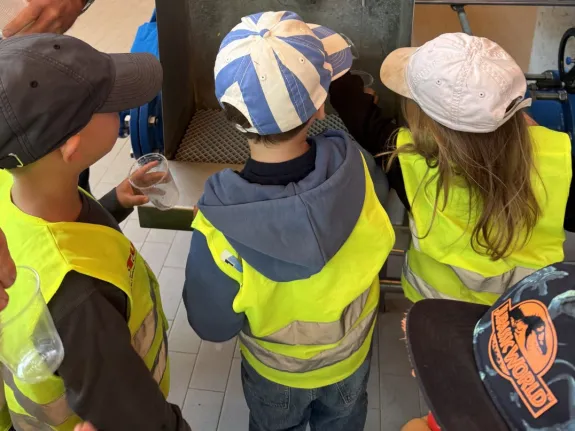 Drei Kinder probieren Trinkwasser