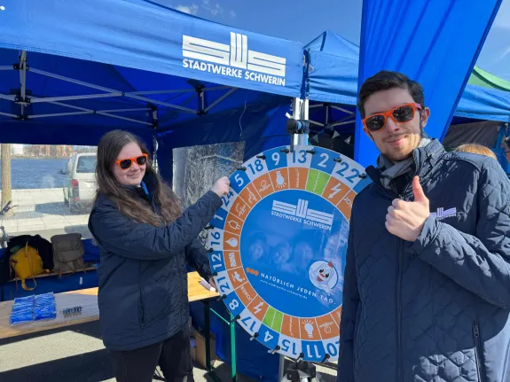 Zwei Auszubildende der Stadtwerke Schwerin stehen vor einem blauen Pavillon.