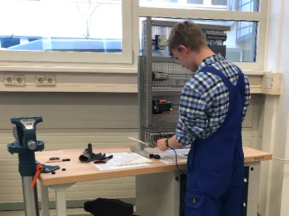 ein gewerblicher Auszubildender arbeitet am Schaltschrank