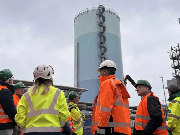 Eine Besuchergruppe steht vor dem zylindrischen Wärmespeicherturm.