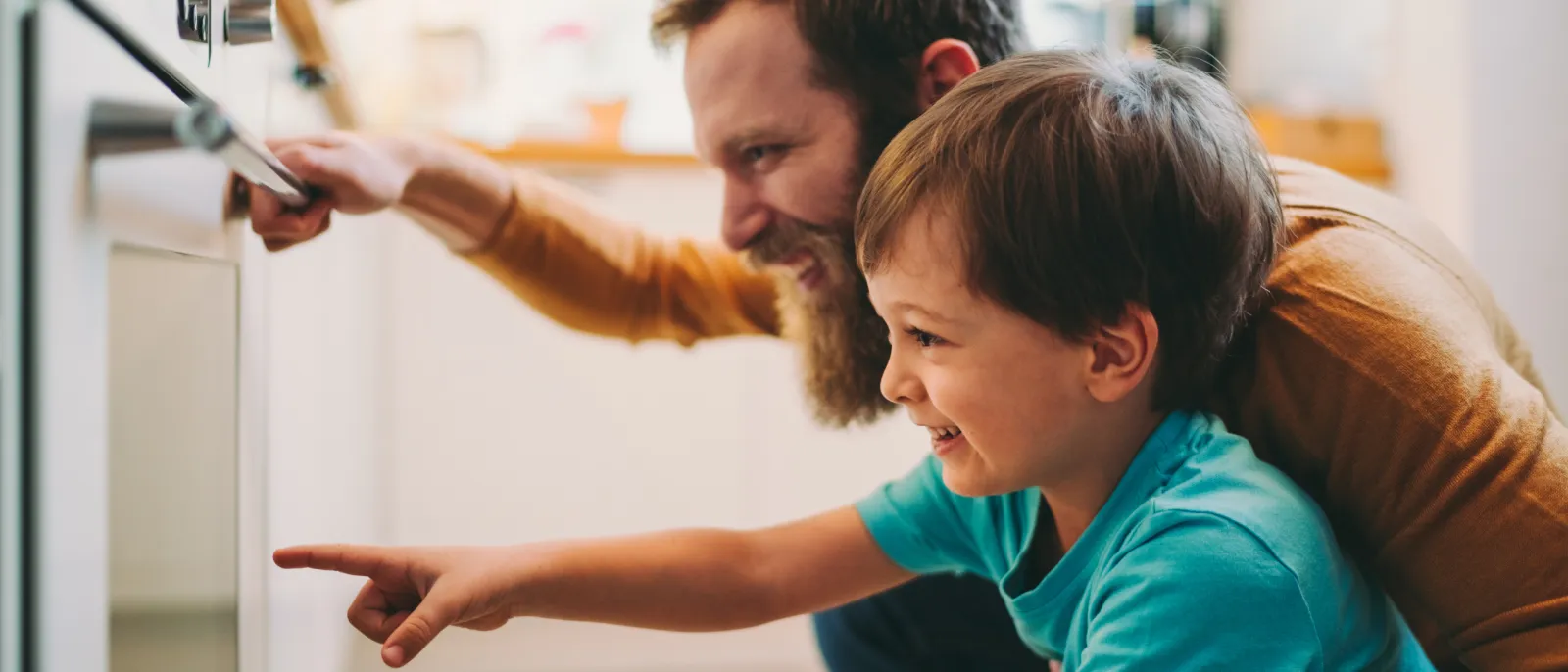 Vater und Sohn schauen begeistert in einen Backofen.