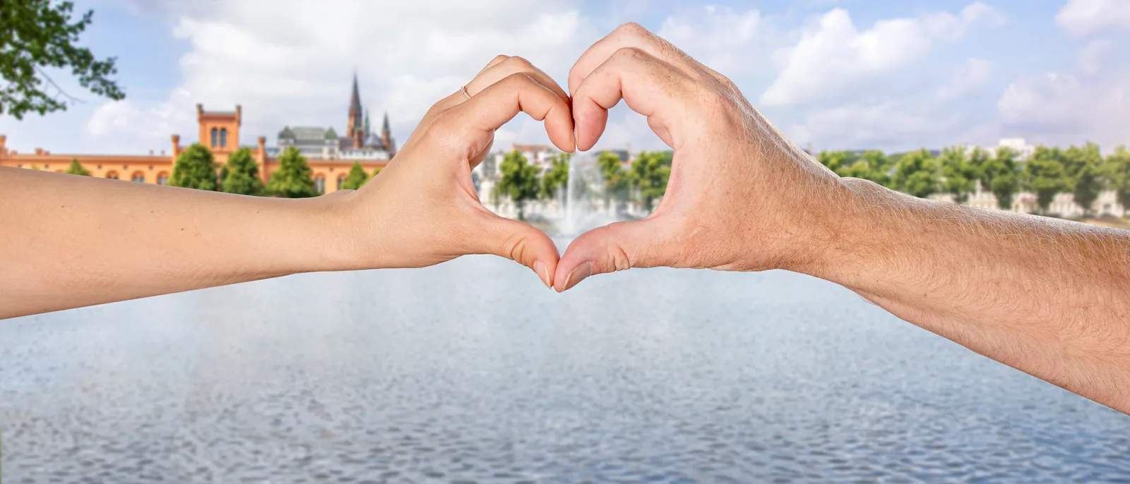 Zwei Hände formen ein Herz am Ufer des Schweriner Pfaffenteichs.