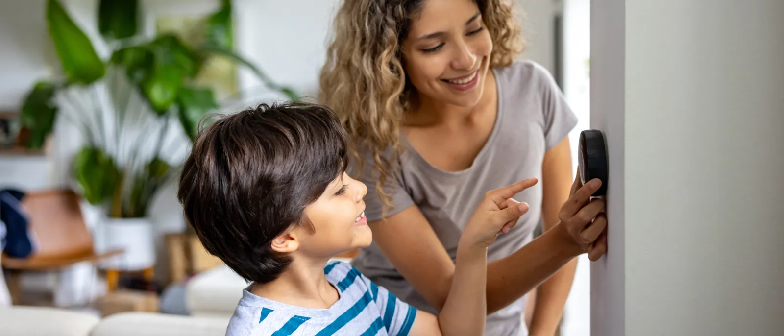 Mutter und Sohn stellen ein Heizungs-Thermostat ein.