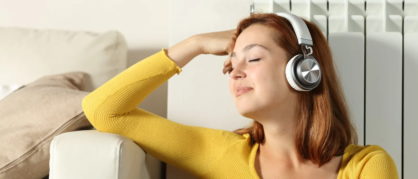 Eine Frau lehnt entspannt an der Heizung und hört Musik.