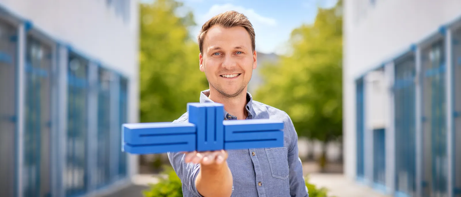 Ein Mann hält das Stadtwerke-Logo auf der Hand und lächelt in die Kamera.