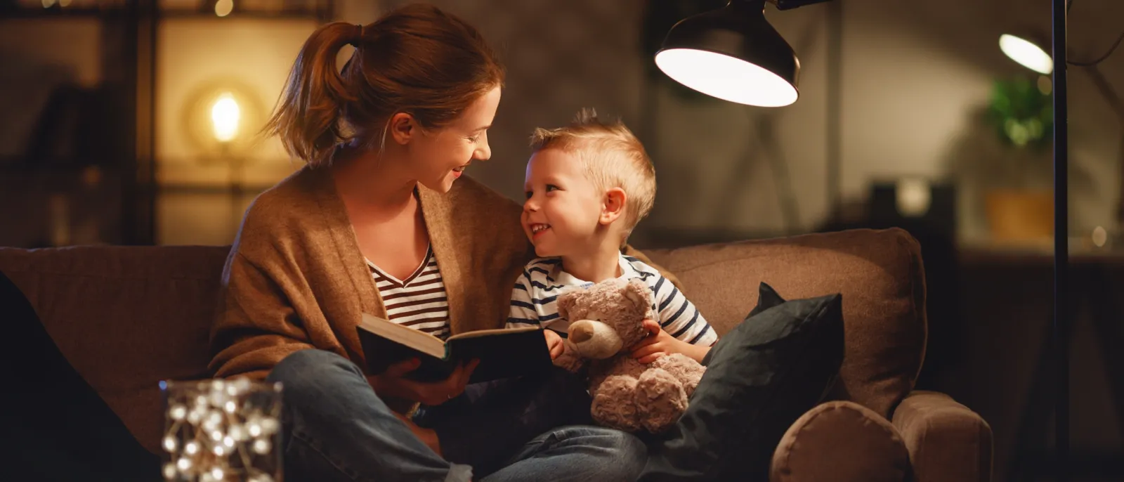 Mutter und Sohn sitzen auf dem Sofa und schauen sich ein Buch an.