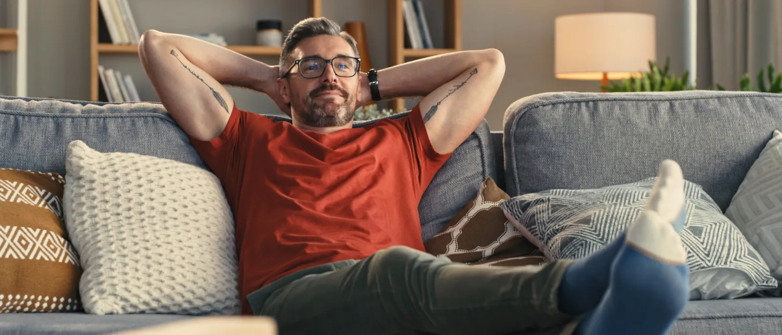 Ein Mann lehnt sich entspannt auf dem Sofa zurück.