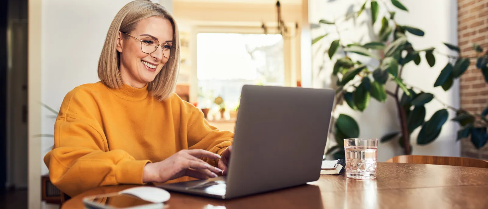 Frau sitzt zuhause am Tisch mit Laptop