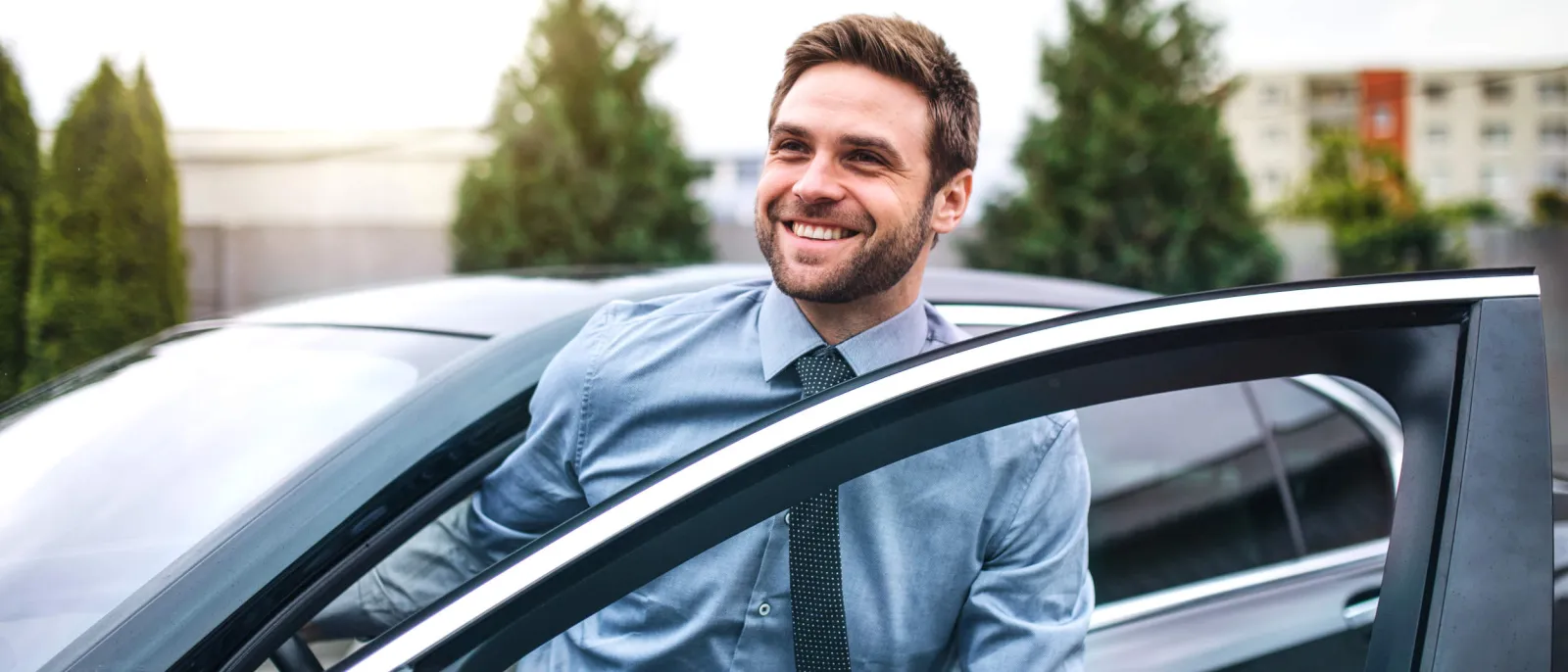 Ein junger Mann mit blauem Hemd, der in der Stadt aus dem Auto steigt.