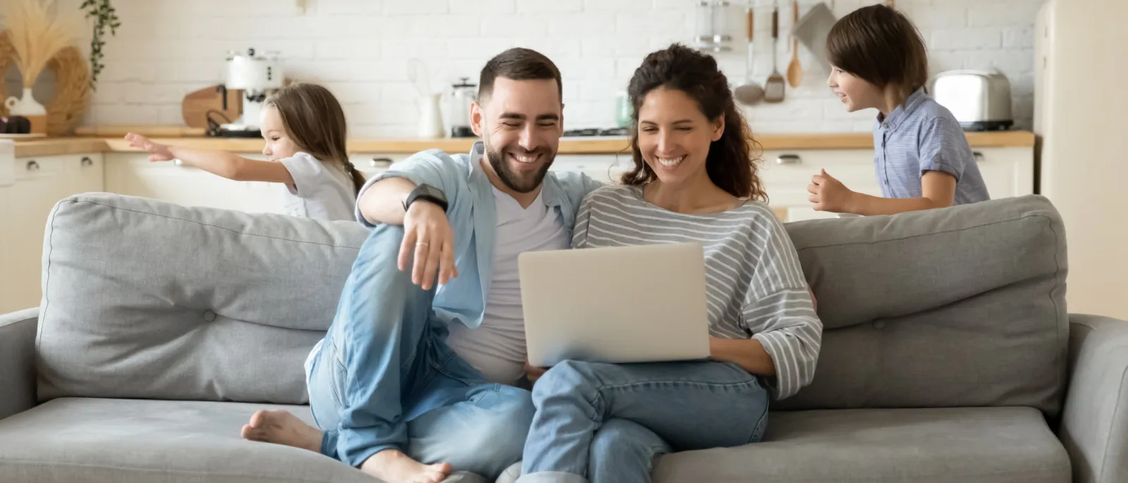 Eltern ruhen auf dem Sofa mit einem Laptop.
