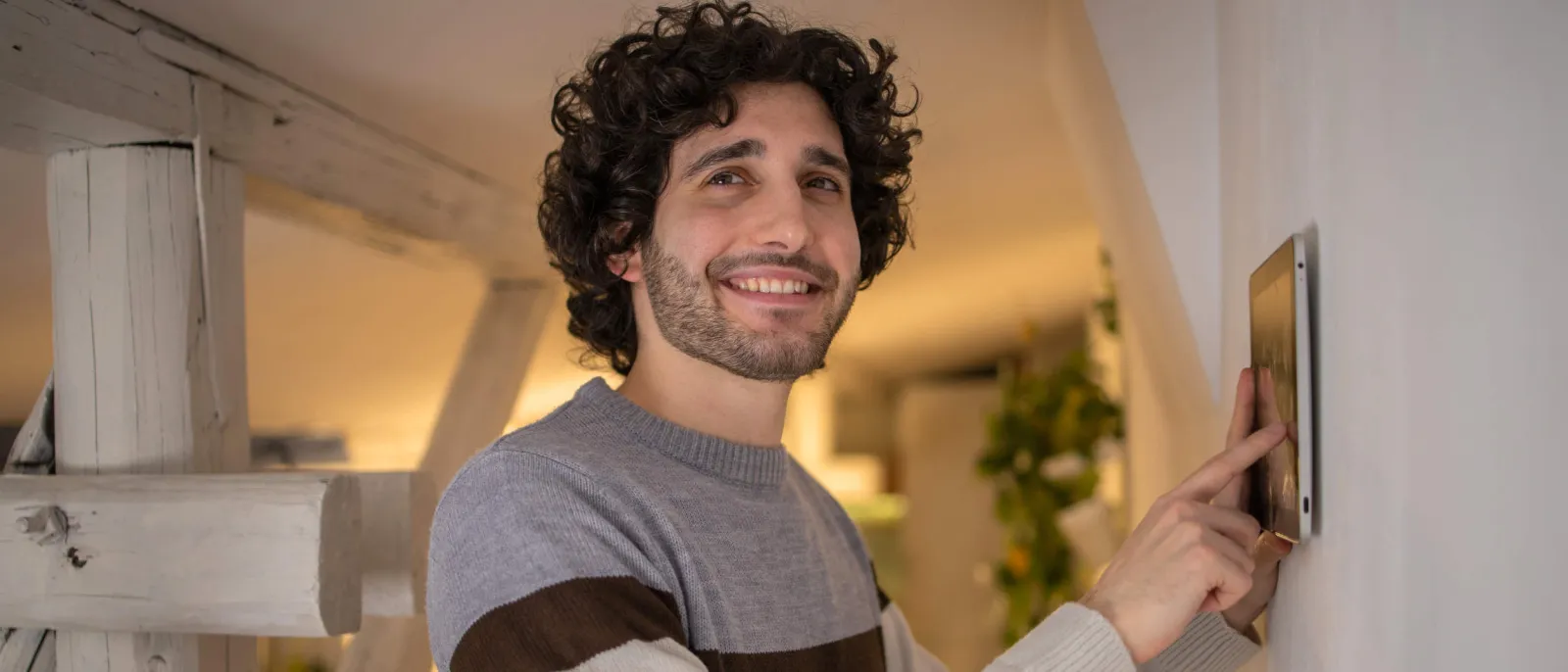 Ein junger Mann stellt die Temperatur zu Hause mit einem Gerät an der Wand ein.