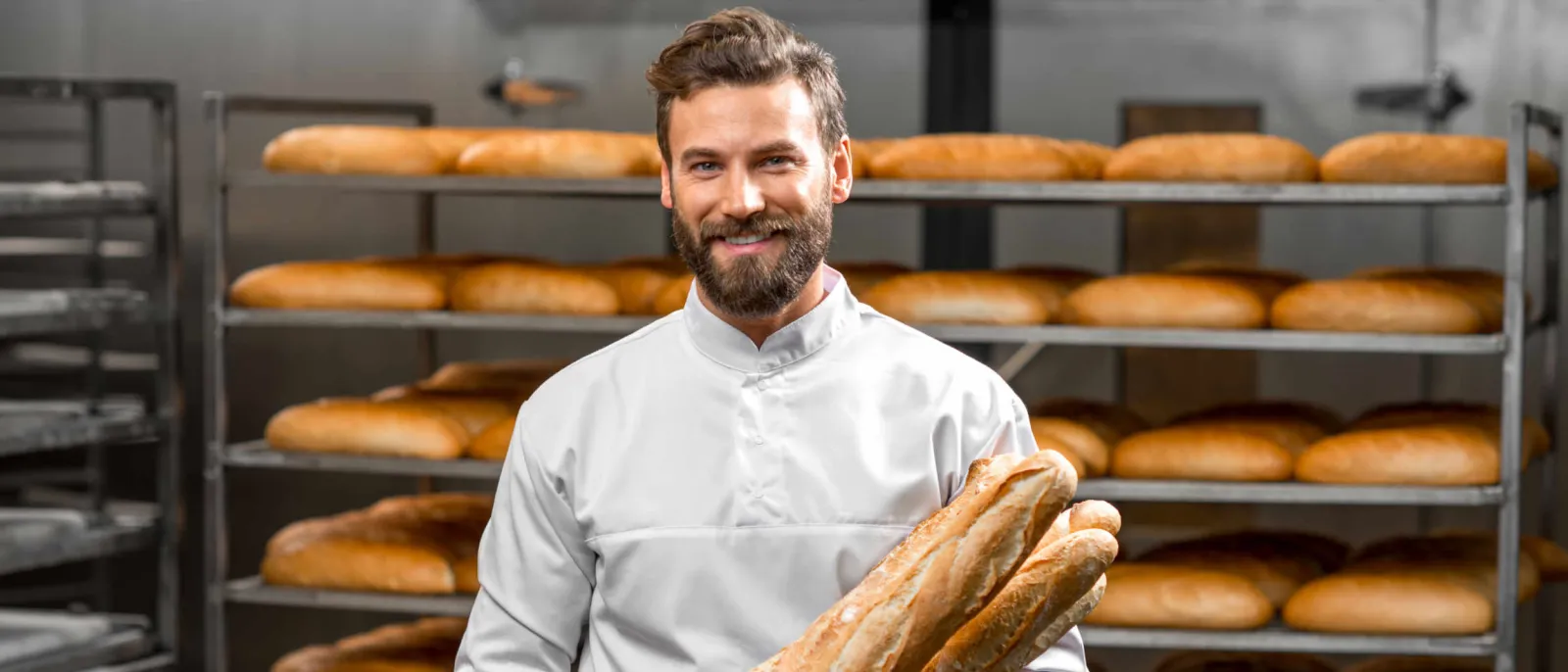 Bäcker steht vor seinen gebackenen Broten, die im mit Gas betriebenen Ofen gebacken wurden.