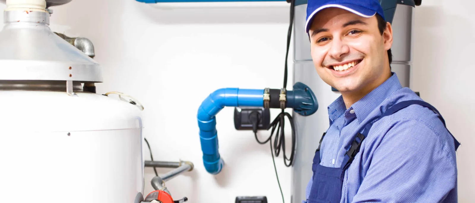 Ein junger Handwerker arbeitet am Warmwasserspeicher.
