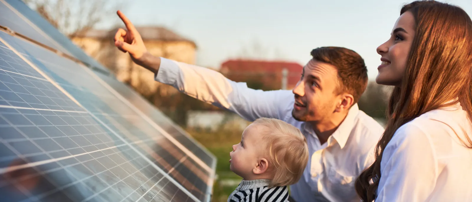 Mann zeigt seiner Familie die Sonnenkollektoren einer Solaranlage