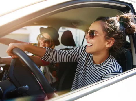 Zwei junge Frauen fahren im Auto und haben Spaß.