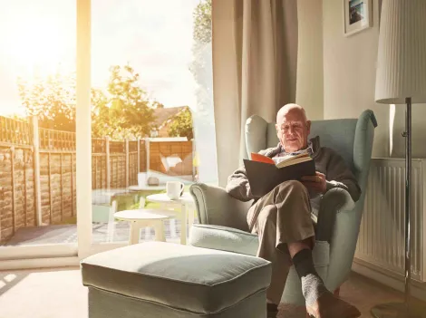Mann liest ein Buch und hat es gemütlich warm Zuhause.