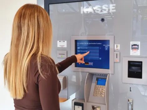 Eine junge Frau tippt auf den Bildschirm des Kassenautomaten im Kundencenter der Stadtwerke.