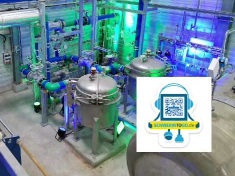 Innenaufnahme des Geothermie-Heizwerks in Schwerin. Zu sehen sind mehrere Kessel, Rohre und Pumpen in beleuchteter Umgebung.