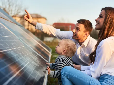 Ein Mann zeigt seiner Familie die Sonnenkollektoren einer Solaranlage.