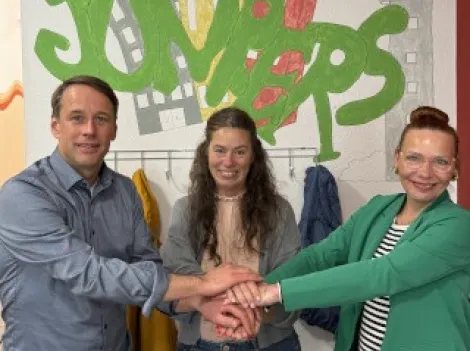 Zwei Frauen und ein Mann legen symbolisch die Hände aufeinander