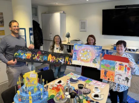 Ein Mann und drei Frauen präsentieren Werke einer Malaktion für Kinder