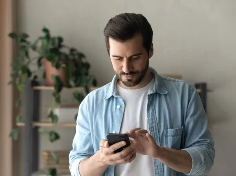 Ein Mann tippt zuhause auf dem Smartphone.