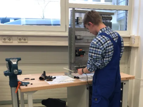 ein gewerblicher Auszubildender arbeitet am Schaltschrank